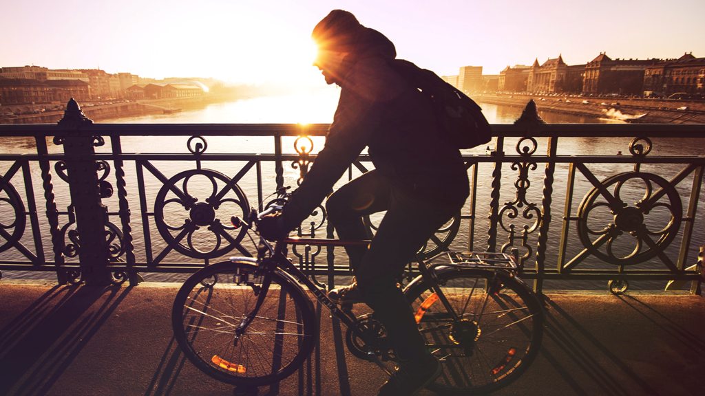 A man cycling across a bridge in Budapest. (Photo: Viktor Keri / Unsplash)